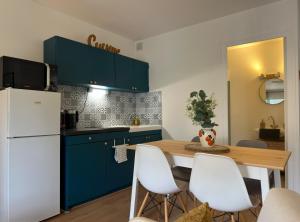 a kitchen with blue cabinets and a table with white chairs at Cocon de douceur en centre ville in Le Puy-en-Velay
