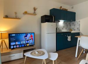 a kitchen with a white refrigerator and a tv at Cocon de douceur en centre ville in Le Puy-en-Velay