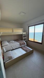 a bedroom with a bunk bed and a large window at Apartamento no Falesias de Pipa - Veleiros 212 in Pipa