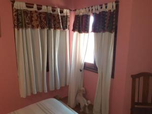 a bedroom with white curtains and a window at MyM in Costa Azul