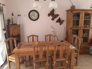 a dining room table with chairs and a clock on the wall at MyM in Costa Azul