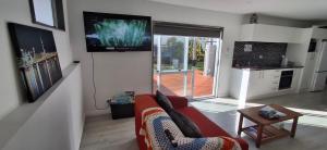 a living room with a couch and a tv on a wall at Holly's Flat Close to Ferry And EV in Wellington