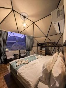 a bedroom with a large bed with a large window at Wadi rum bubble camp in Wadi Musa