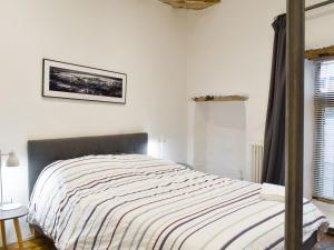 a bedroom with a bed with a striped blanket at Hogwood Cottage in Knaresborough