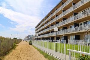 a building on the beach next to a fence at Dunes Suites Oceanfront in Ocean City