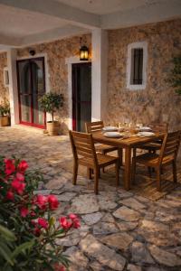a wooden table and chairs on a stone patio at Alma-Maroon Klara & Rachel in Drymon +35 photos
