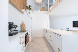 a white kitchen with white cabinets and a staircase at Coolum Beach Retreat in Coolum Beach