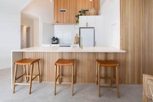 a kitchen with two bar stools and a counter at Coolum Beach Retreat in Coolum Beach