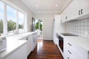 a kitchen with white counters and a large window at Glass House Cottage in Glass House Mountains