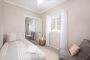 a bedroom with a bed and a window and a chair at Glass House Cottage in Glass House Mountains