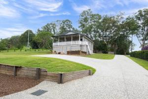 a large white house with a grassy yard at Glass House Cottage in Glass House Mountains +7 photos