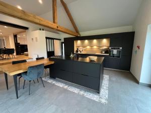 a kitchen with black cabinets and a wooden table at Le Domaine Endila in Munster