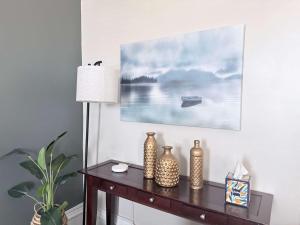 a table with vases on it with a painting on the wall at Suite One King Bed 2TVs Free Parking & museums in Richmond