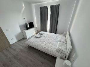 a white bedroom with a bed and a window at Luca House in Remetea Mare