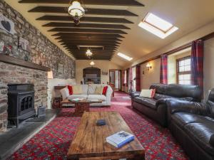 a living room with leather furniture and a stone wall at Stoney Cottage in Narberth