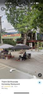 a person sitting under an umbrella on a street at Xuân Thành Homestay in Vũ Lâm