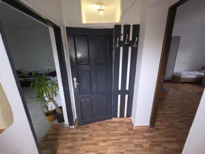 a hallway with a black door and a plant at Matei Apartament in Tîrnăveni