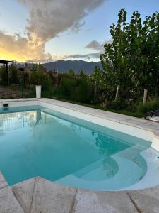 a large blue swimming pool with a sunset in the background at el sueño in Las Compuertas