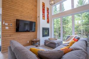 a living room with a couch and a flat screen tv at Le Kouzy - Spa, Foosball, Pool table, Game Room in Sainte-Lucie-de-Doncaster