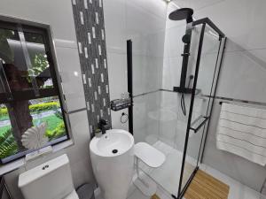 a bathroom with a toilet and a sink and a window at Indulge Deluxe Accommodation in Middelburg