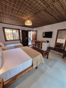 a bedroom with a large bed and a television at Pousada Villa Gûyrá in Trancoso