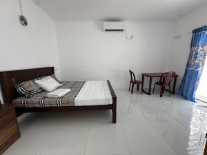 a bedroom with a bed and a table and chairs at Andrella Rest House in Mannar