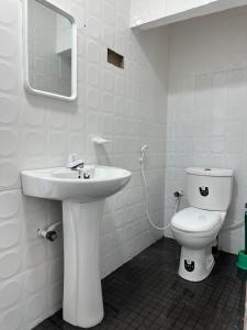 a white bathroom with a toilet and a sink at Andrella Rest House in Mannar
