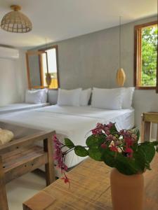 a bedroom with two beds and a vase with flowers on a table at Pousada Villa Gûyrá in Trancoso +59 photos
