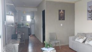 a living room with a white couch and a kitchen at Flat vista mar in Paulista