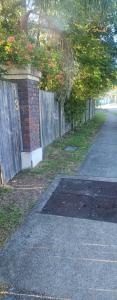 a sidewalk next to a fence with red flowers at Aztec Adress 133 Beckett Road, mixed shared accommodation in Brisbane