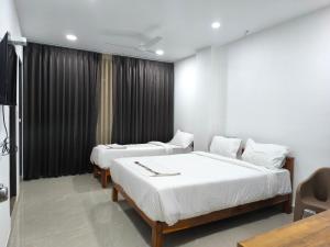 two beds in a room with black curtains at Hotel Visara Grand in Gokarna
