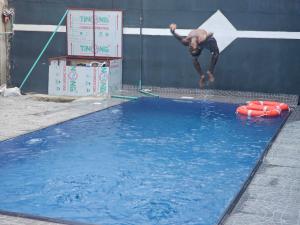 a man jumping into a pool of water at Hen-Cap Apartment Services in Agege