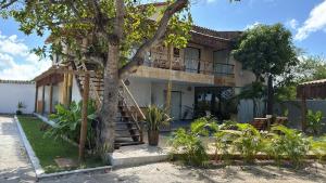 a house with a tree in front of it at Suítes House Refúgio Fortim in Fortim