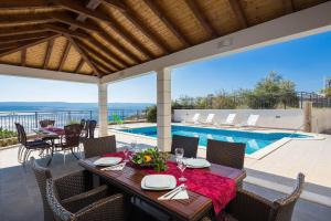 een patio met een tafel en stoelen en een zwembad bij Beachfront Apartments Lara in Omiš