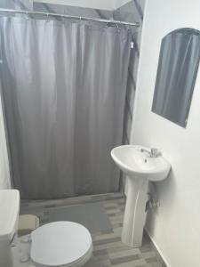 a white bathroom with a toilet and a sink at Plata View Center Habitacion 2D in Monte Plata