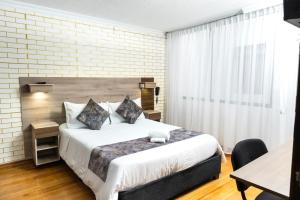 a bedroom with a bed with a brick wall at Hotel Versalles Boutique in Pasto