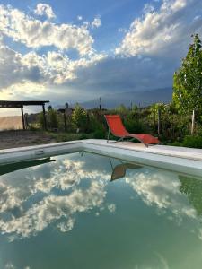 a red chair sitting next to a swimming pool at el sueño in Las Compuertas