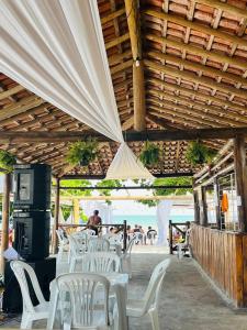 a group of white tables and chairs in a restaurant at Pousada Sol e Mar in Saubara