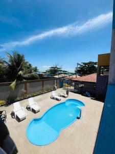 a swimming pool with lounge chairs and a blue swimming pool at Pousada Sol e Mar in Saubara