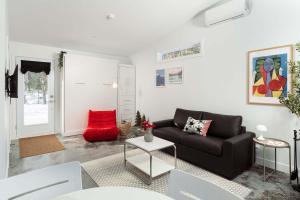 a living room with a black couch and a red chair at The Lofti in Sainte Béatrix