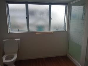 a bathroom with a toilet and a window at Budget shared accommodation holiday room spring city in Tauranga