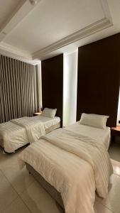 two beds in a hotel room with white sheets at وادي برزان للشقق المخدومة in Hail +36 photos
