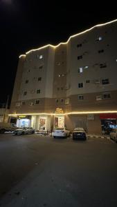 a large building with cars parked in a parking lot at وادي برزان للشقق المخدومة in Hail