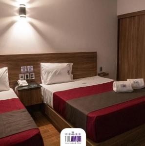 a hotel room with two beds and a telephone at Tulamor Love Suites & Villas in San Lorenzo