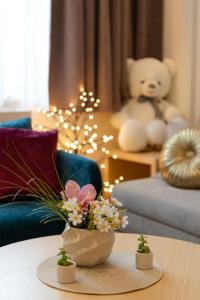 a table with a vase of flowers and a teddy bear at Z terme Harmony in Vrnjačka Banja +75 photos