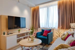 a living room with a tv and a blue chair at Z terme Harmony in Vrnjačka Banja