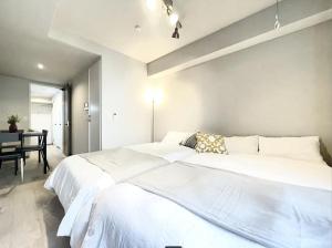 a bedroom with a large white bed and a table at TIC HOTEL Hisayaodorisakae in Nagoya