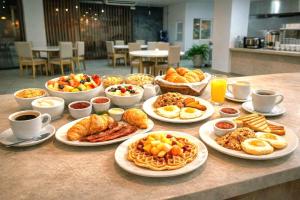 a table with plates of breakfast foods and drinks at Hotel Lotto Boutique in Cali