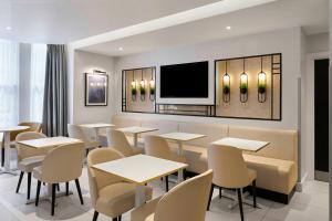 a restaurant with tables and chairs and a flat screen tv at Four Points Flex by Sheraton London Kensington Olympia in London
