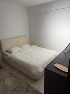 a white bedroom with a bed and a table at Deluxe Apartment 1 in Gnjilane